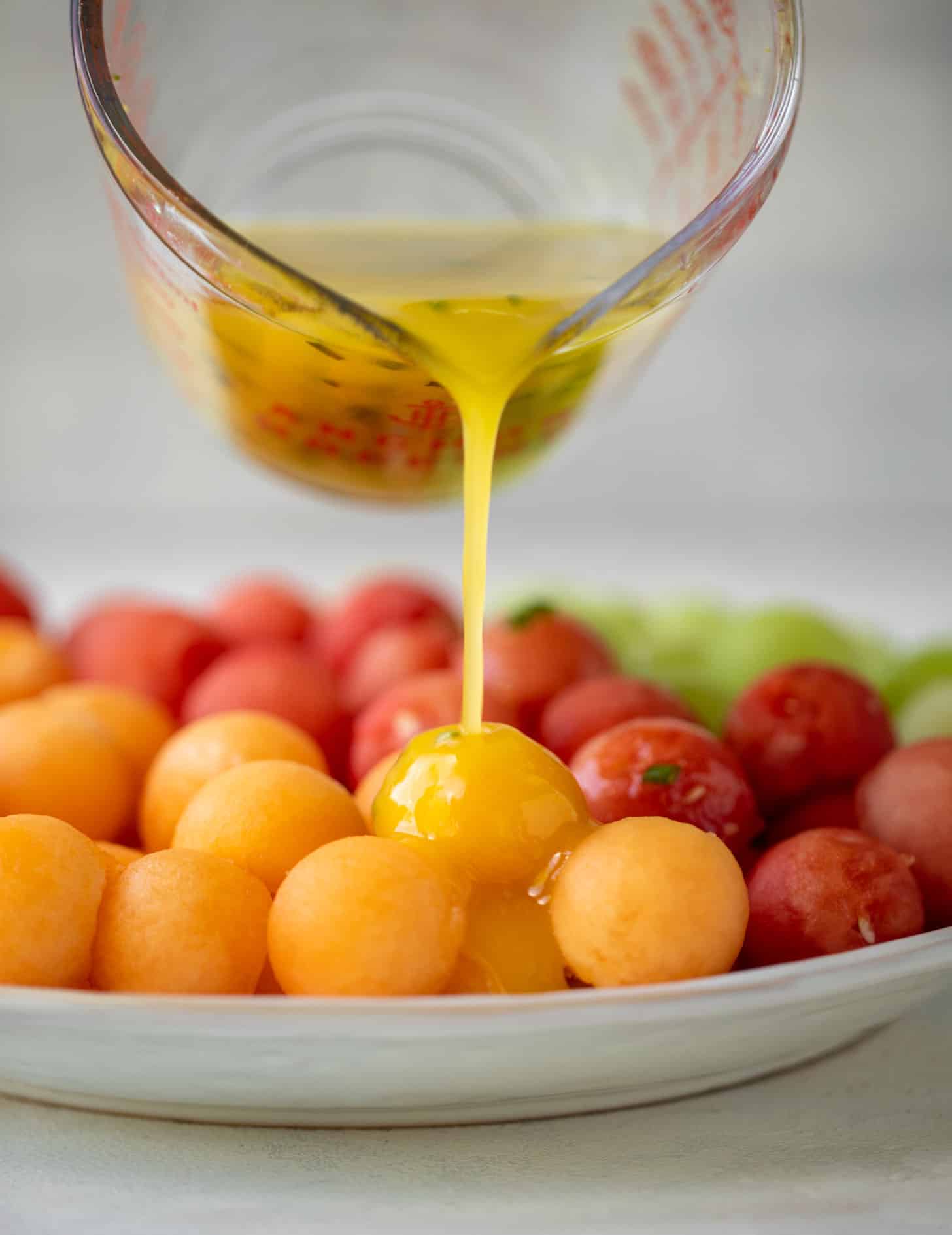 pouring lemon vinaigrette on melon